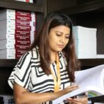 A young female student reading a business research book in a library setting.