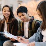 Group of college students studying together on campus in autumn.
