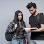 a man and a woman are looking at a book